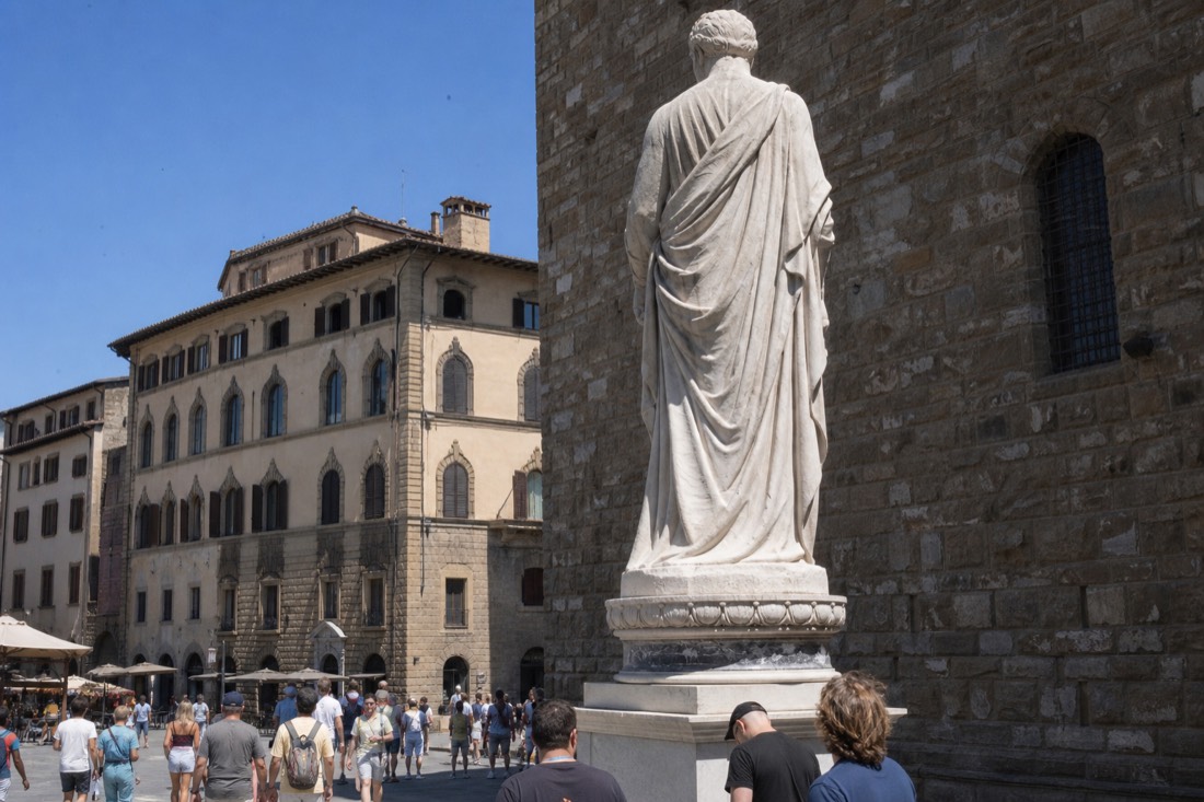 The replica of Michelangelo's David seen from behind against the stone tower of Palazzo Vecchio in Piazza della Signoria Florence