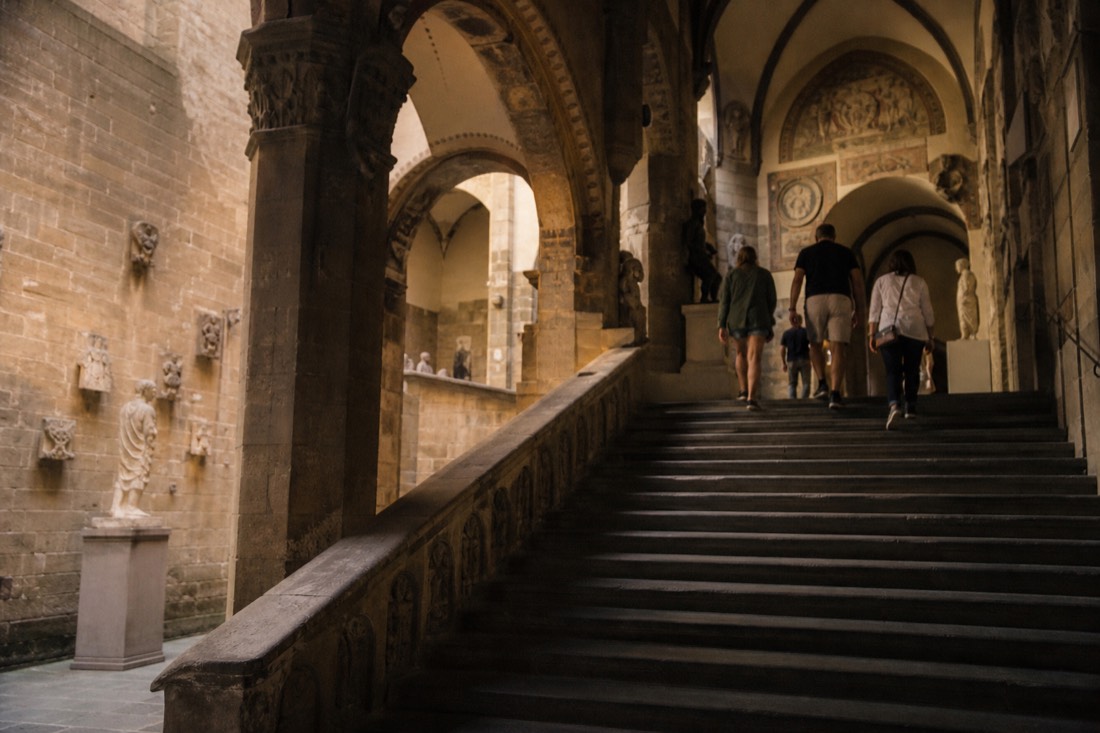 Interior stone courtyard and staircase of the Bargello museum in Florence with sculpture in the vaulted halls
