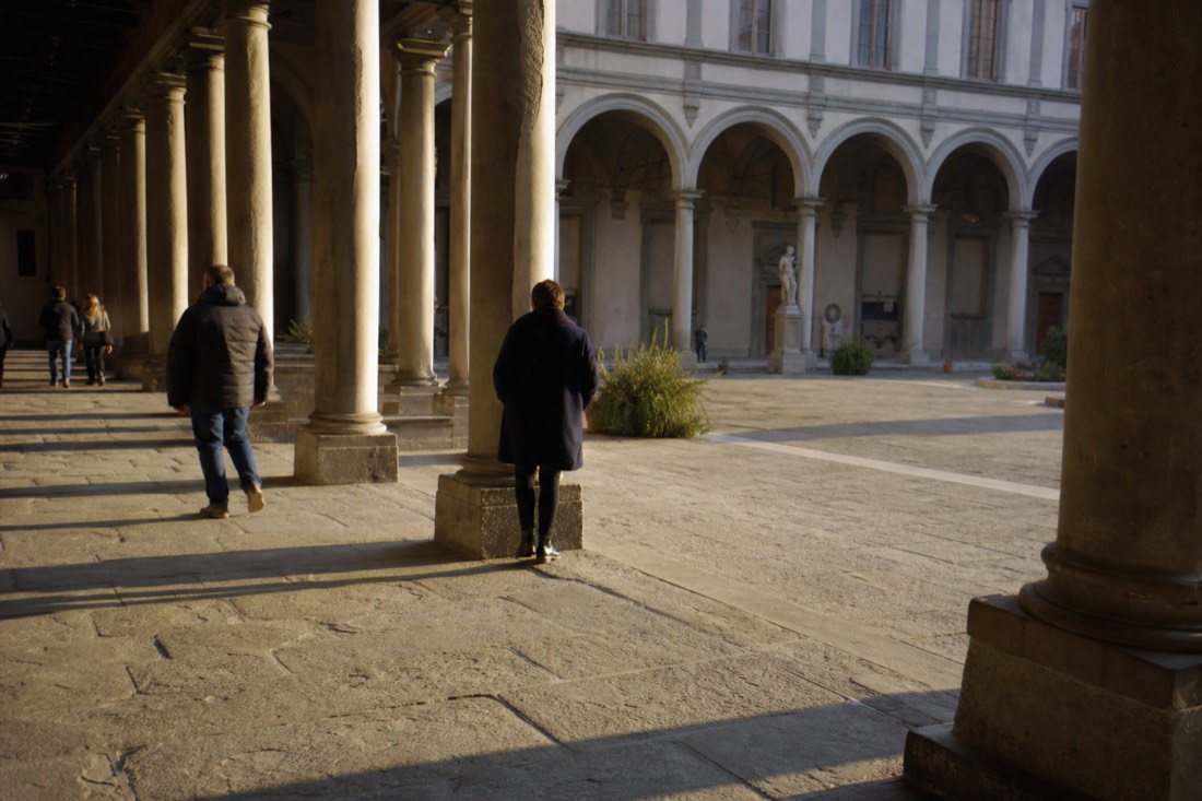 Sunlit interior courtyard of a renaissance palazzo in Florence with long shadows across stone columns