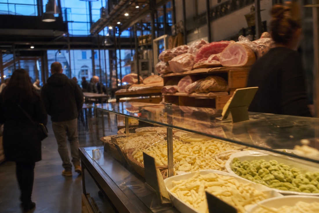 Bustling upstairs food hall counters piled with fresh pasta and cured meats at the Mercato Centrale in the San Lorenzo district of Florence