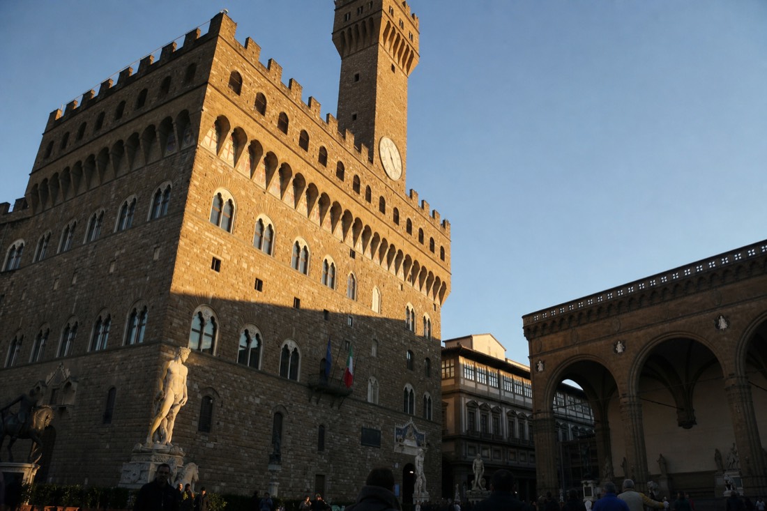 The stone facade of Palazzo Vecchio in Florence at the spot where David originally stood, the town hall tower rising against a clear sky