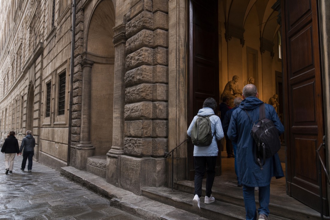 Early visitors entering the Accademia Gallery entrance on Via Ricasoli in Florence under soft morning light