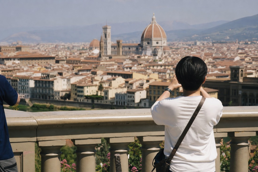Sun-drenched central Florence rooftops and the Duomo dome shimmering under a hazy hot summer sky