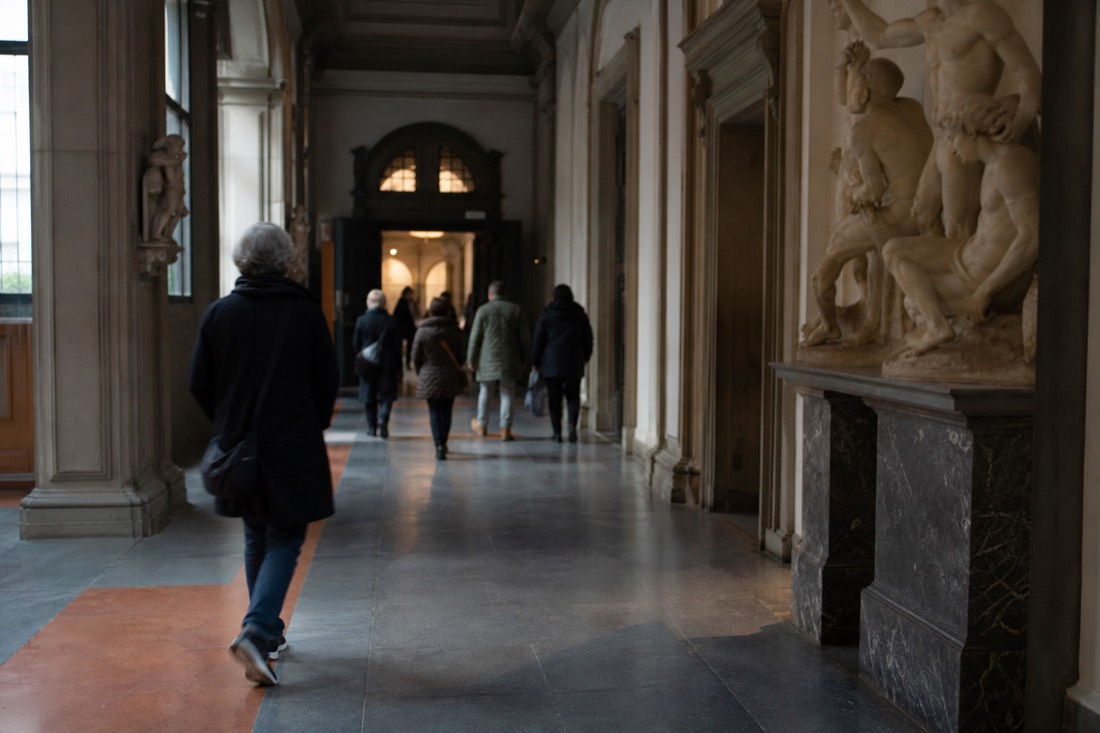 Visitors quietly photographing the marble David with phones under the domed skylight of the Accademia Gallery tribune in Florence