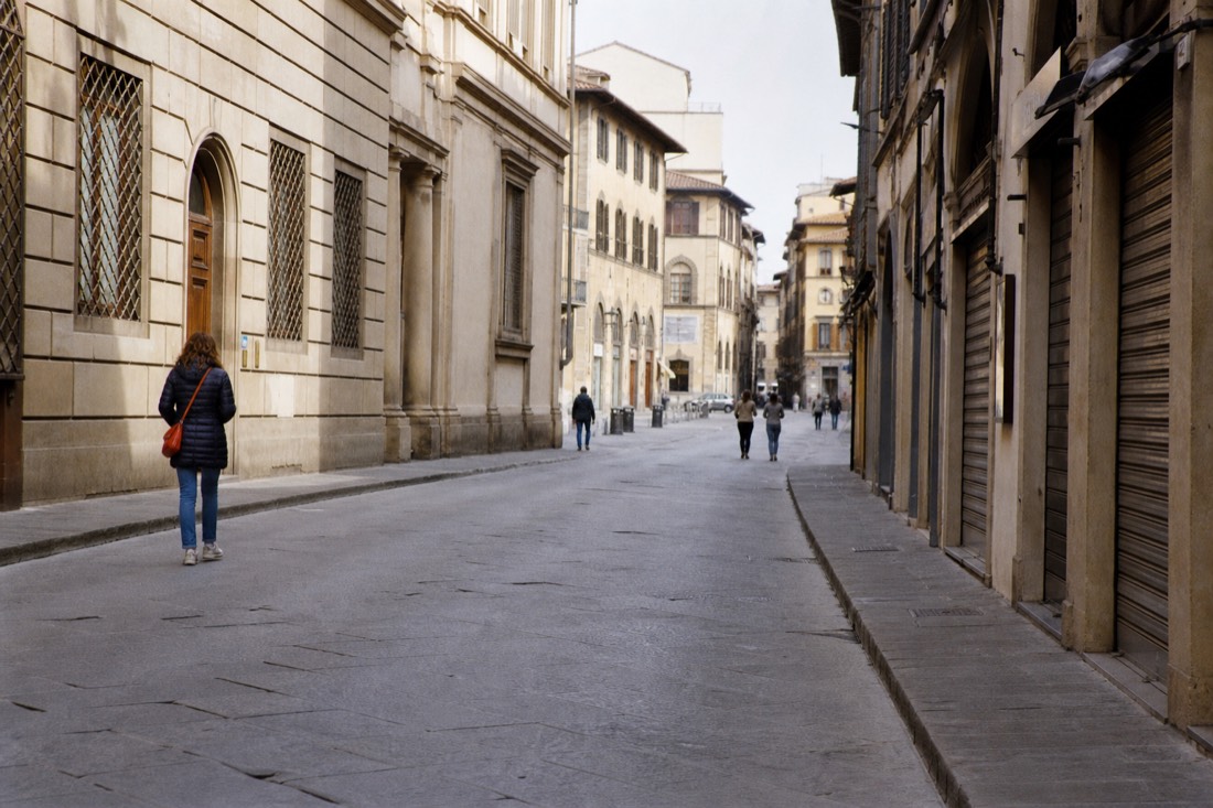 Sunday morning sun on an empty Via Ricasoli with the Accademia Gallery facade and closed shop shutters in Florence