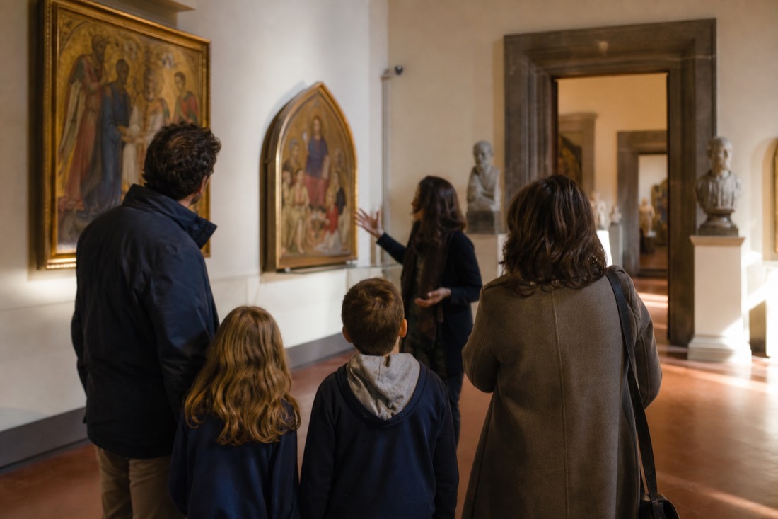 A family with two children listening to a private guide in a quiet gallery room of the Accademia with gold-ground paintings on the walls