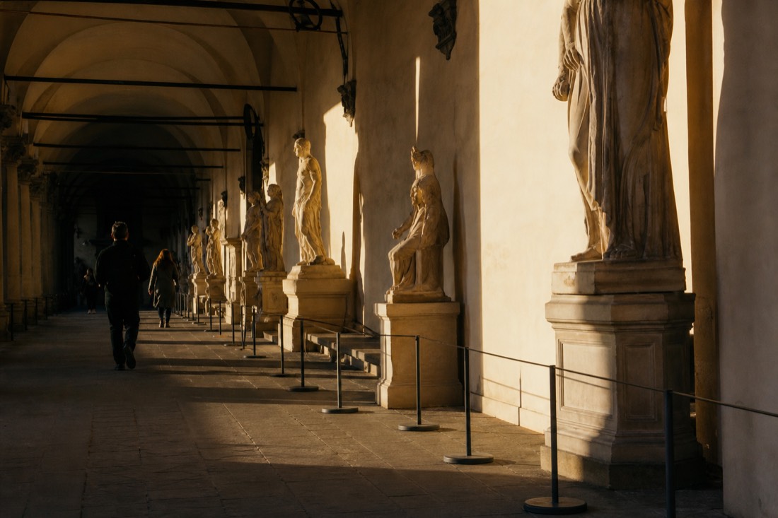 Late afternoon light falling across the nearly empty sculpture corridor of the Accademia Gallery in Florence