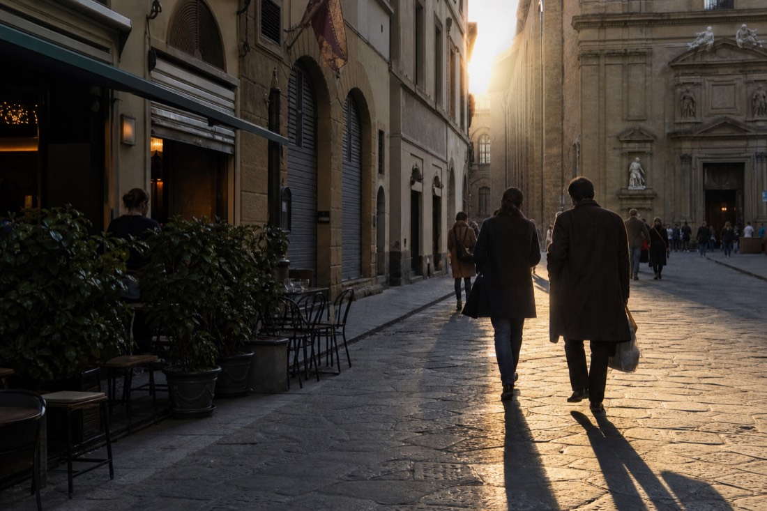 Early light on a quiet Florence street with cafe shutters half open and the Accademia doorway down the block