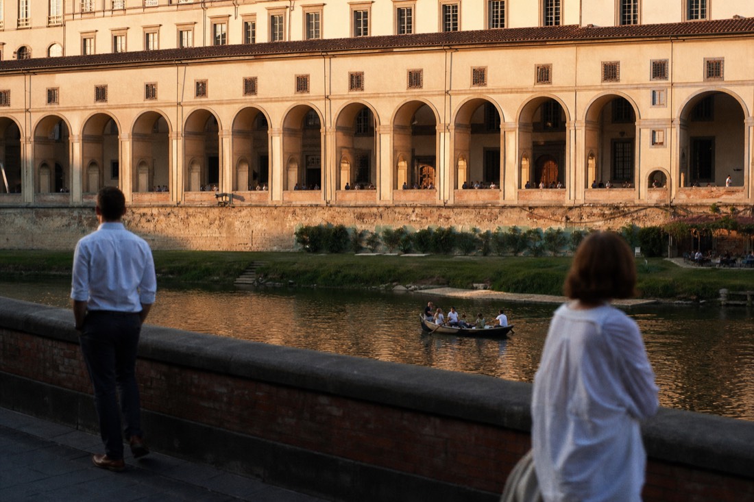View across the Arno river toward the Uffizi Gallery colonnade in late golden afternoon light