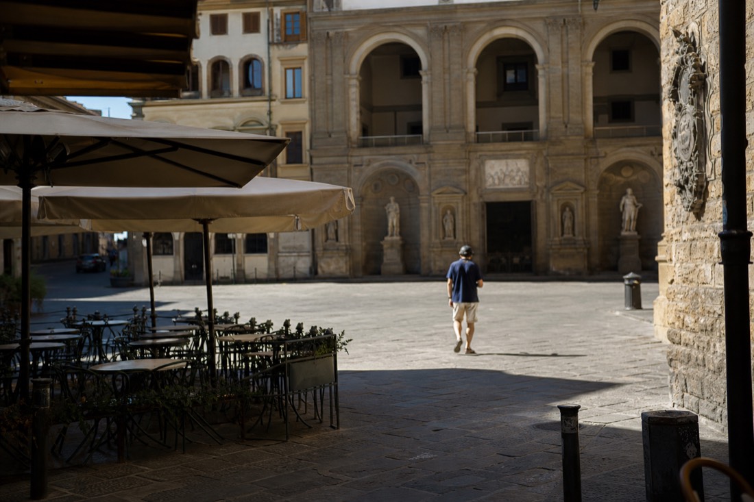 Sunlit Piazza San Marco in Florence at early morning with empty cafe tables and a quiet street corner
