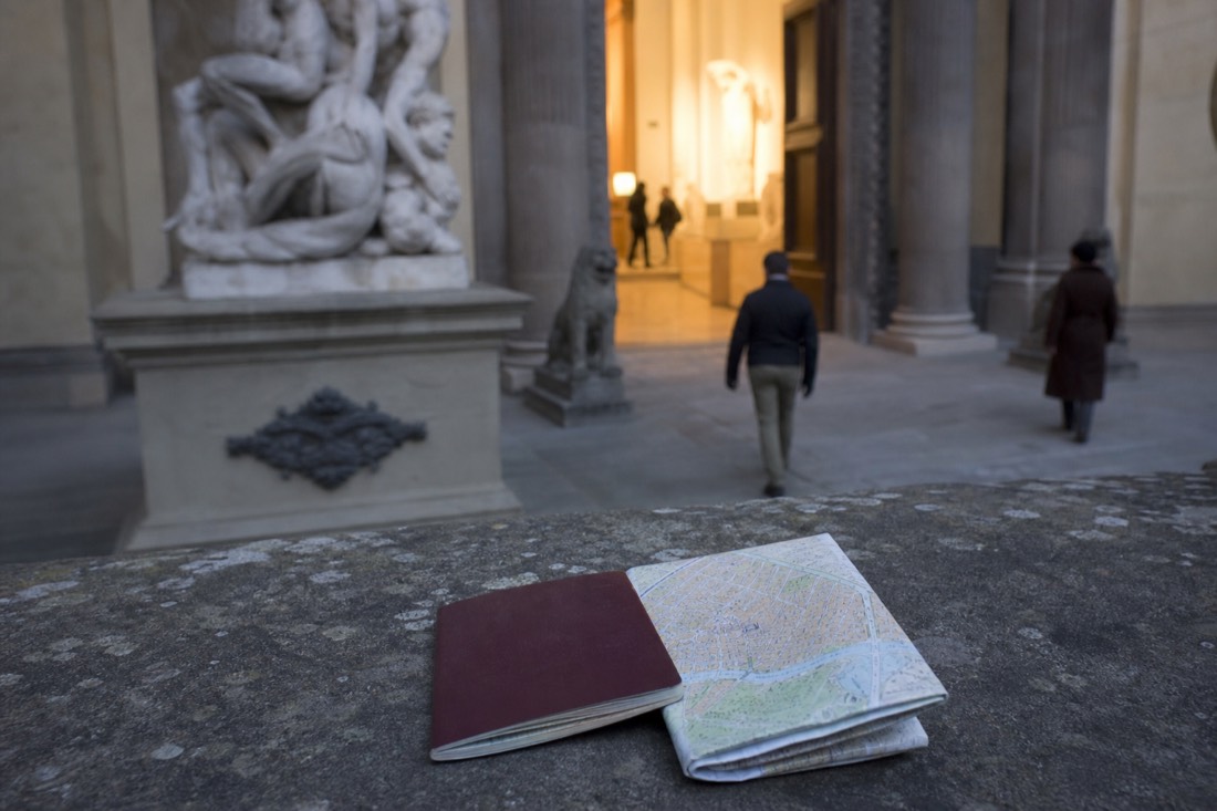 A passport and a folded Florence map resting on a stone ledge outside the Accademia entrance in Florence