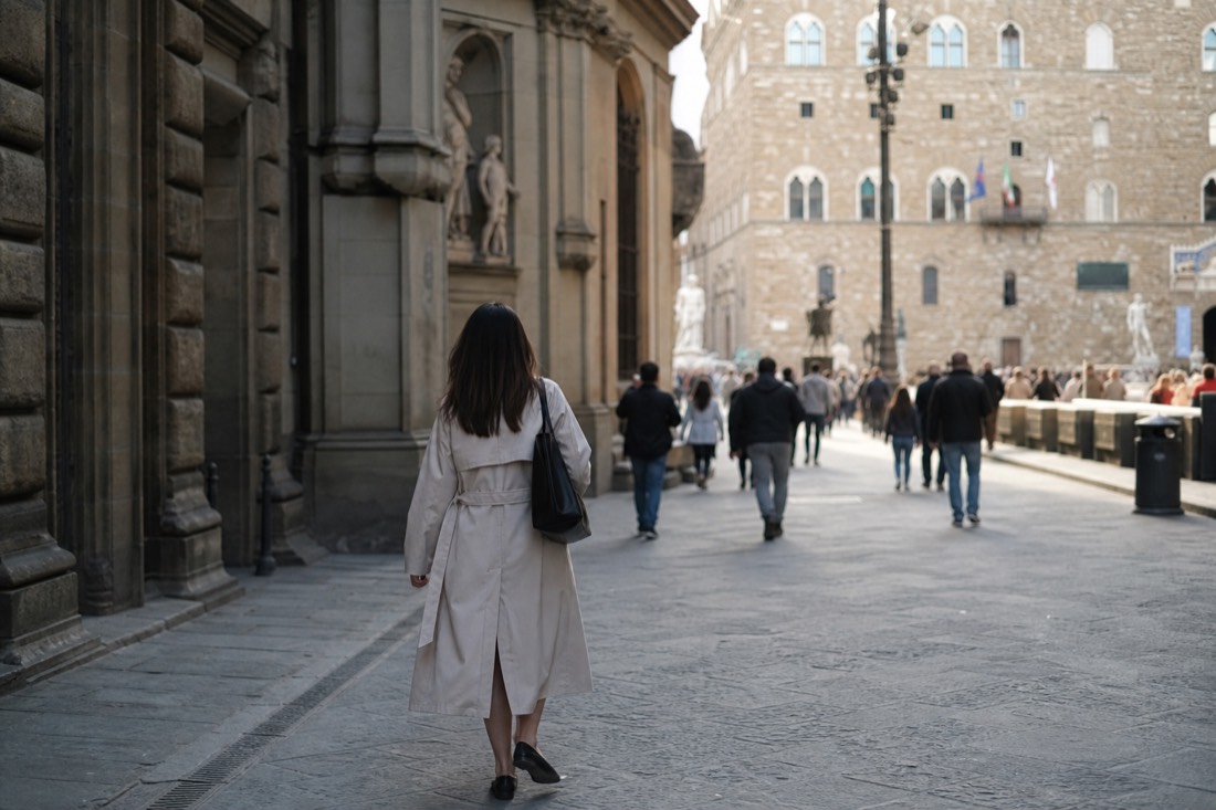 A visitor walking between two Florence landmarks along a sunlit street connecting the Accademia quarter to the Piazza della Signoria