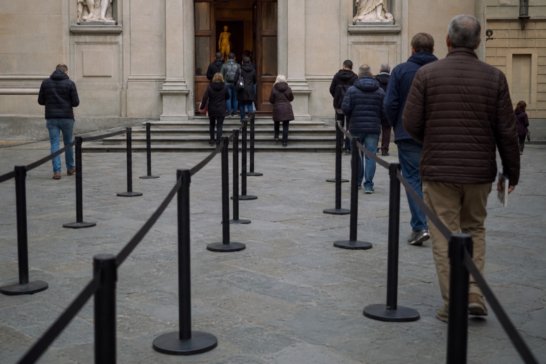 Two empty roped queue lanes leading toward the entrance doors of the Accademia Gallery on Via Ricasoli