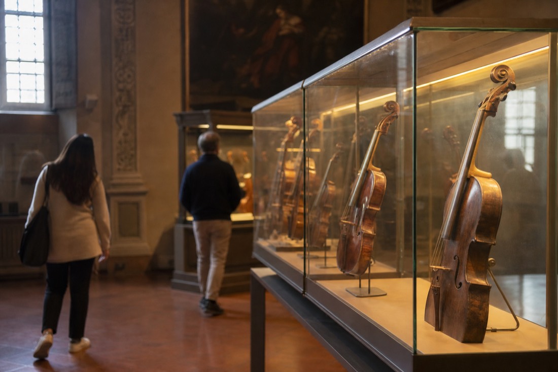 Unfinished marble Prisoners by Michelangelo lining a gallery in the Accademia in Florence with visitors looking closely at the rough-cut stone