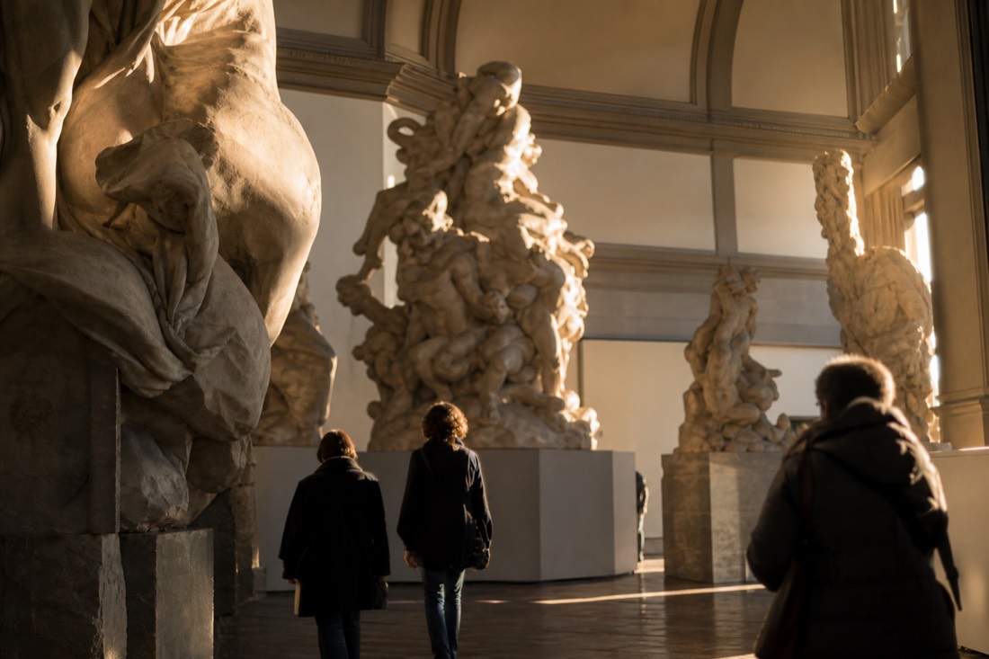 A towering off-white plaster sculpture group of twisting figures filling the Hall of the Colossus at the Accademia Gallery in Florence