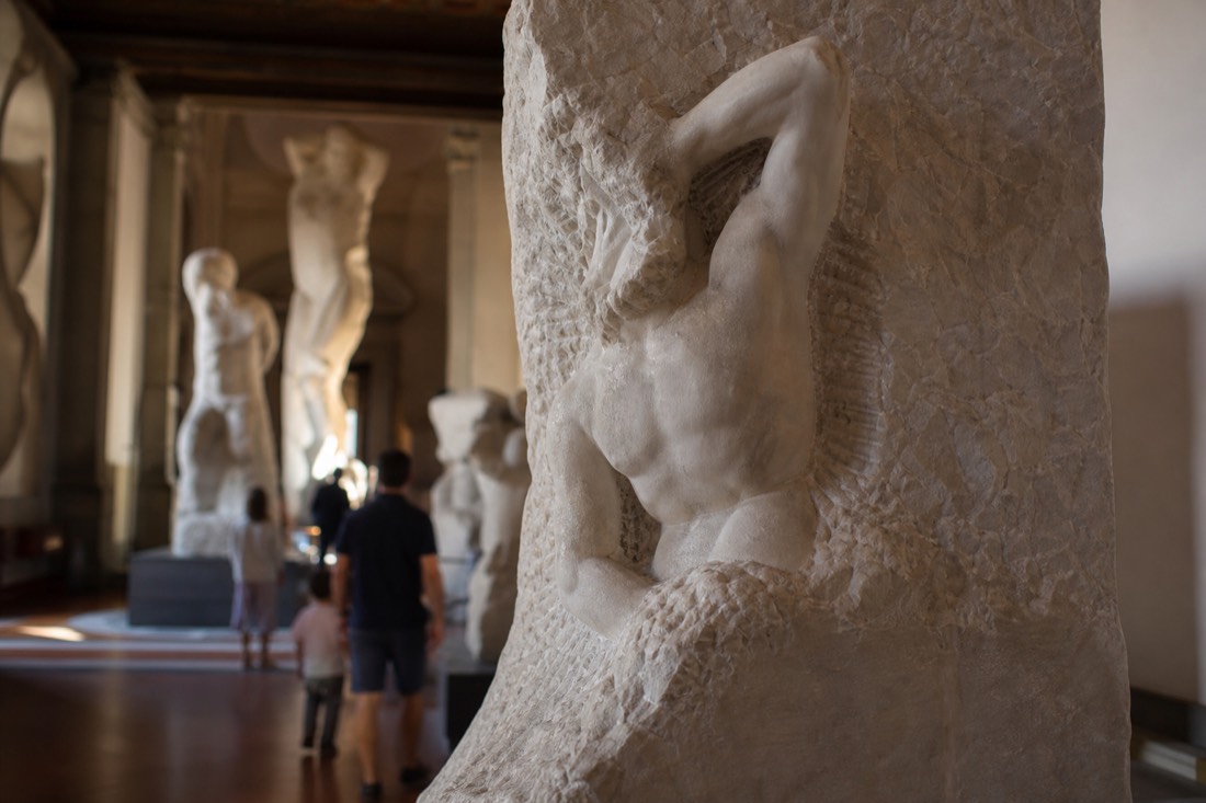 Close view of a half-carved Michelangelo Prisoner emerging from rough uncut marble in the Accademia Gallery in Florence
