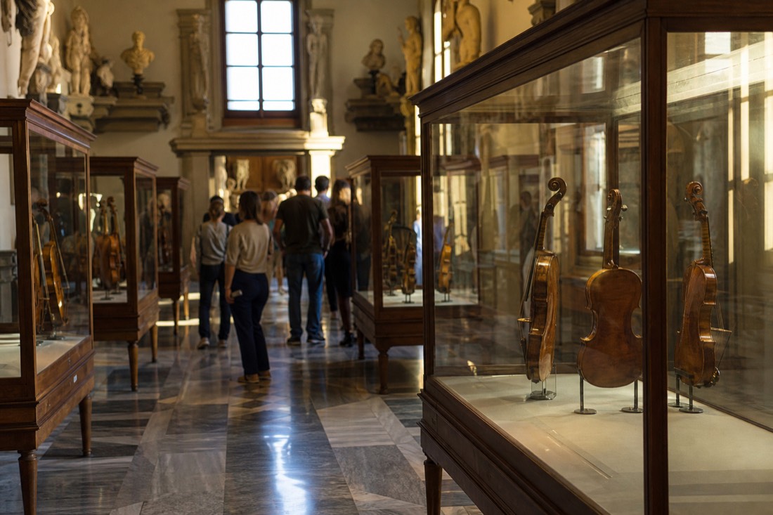 Antique stringed instruments including violins and violas displayed in glass cases in the musical instruments rooms of the Accademia Gallery in Florence