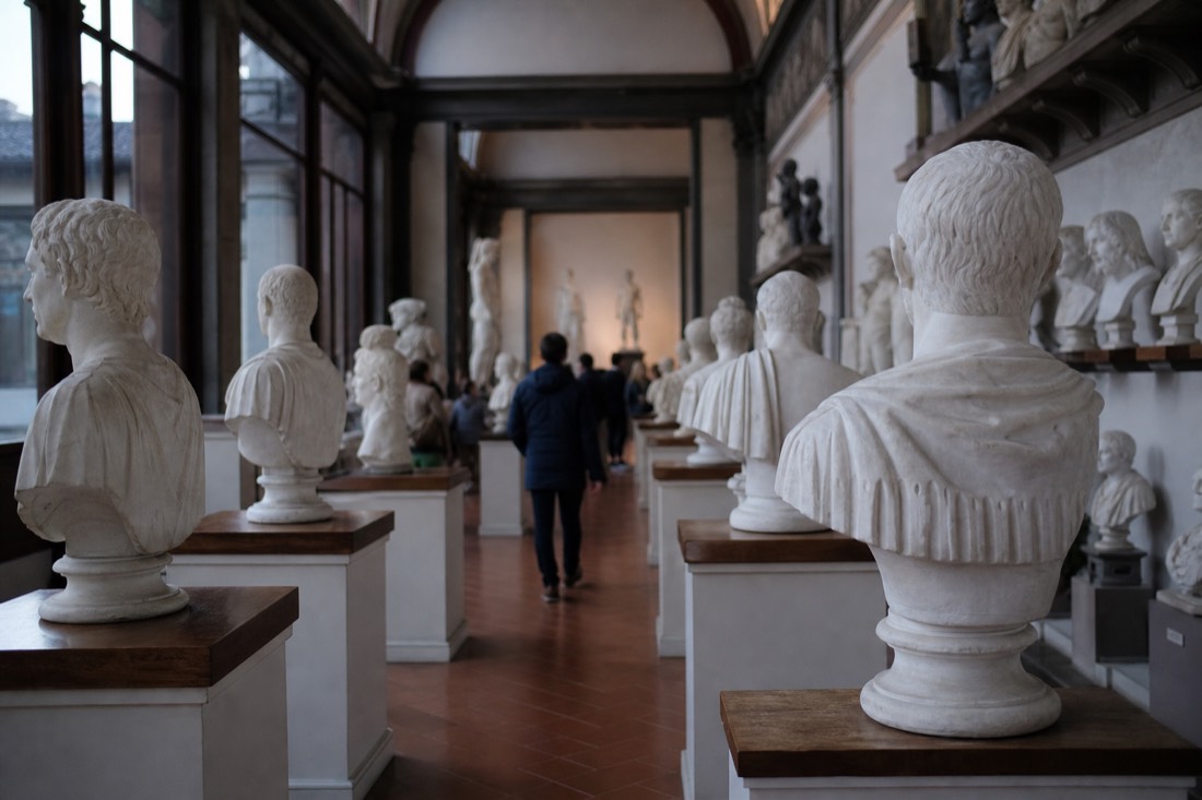 Rows of white plaster portrait busts and figure casts filling the Gipsoteca hall at the Accademia Gallery in Florence