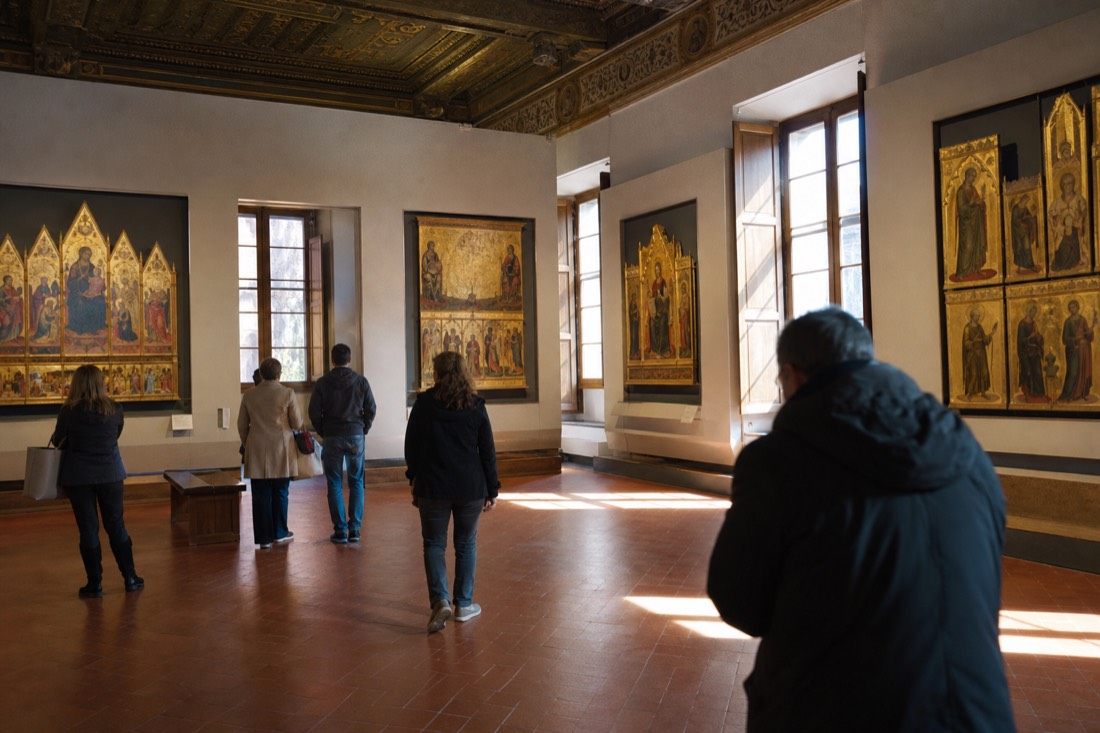 Rows of gold-ground Trecento panel paintings glowing on the walls of a quiet upstairs room at the Accademia Gallery in Florence