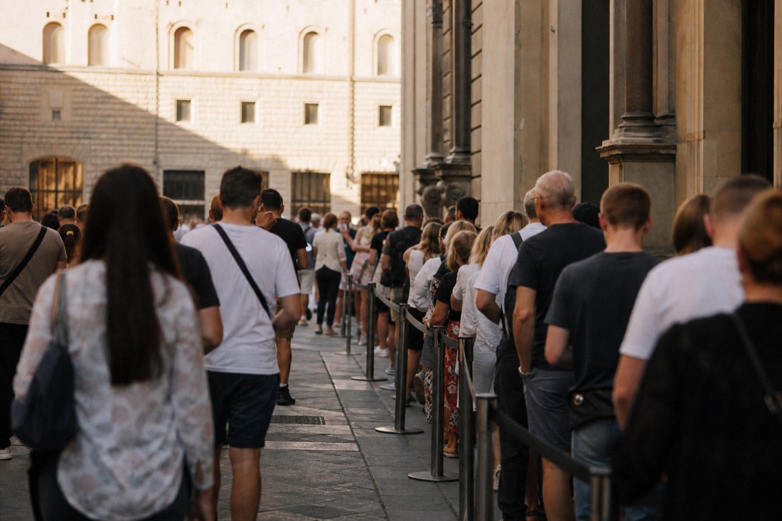Morning queue outside the Accademia Gallery entrance on Via Ricasoli, Florence, where skip the line ticket holders walk past